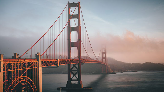 Photo of the golden gate bridge with mist at sunset.